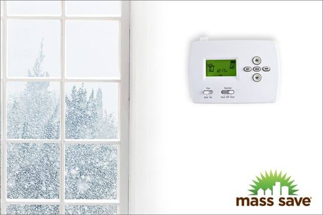 snowy window next to thermostat with mass save logo