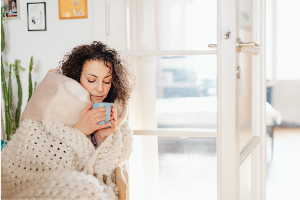 Woman wrapped in blanket holding mug