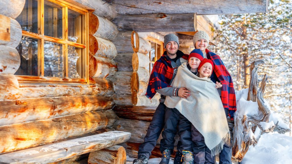 family standing outside of cabin in winter