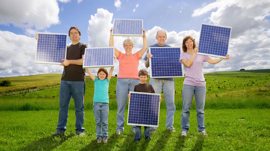 a multi-generational family in a field holding small solar panels