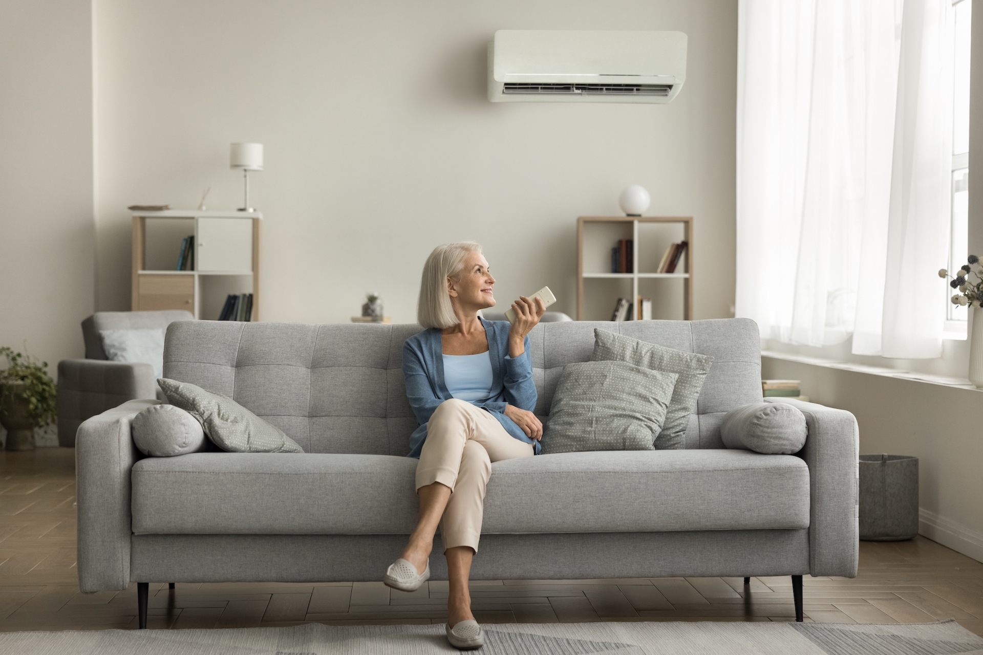 older women turning on the mini split heat pump in her living room