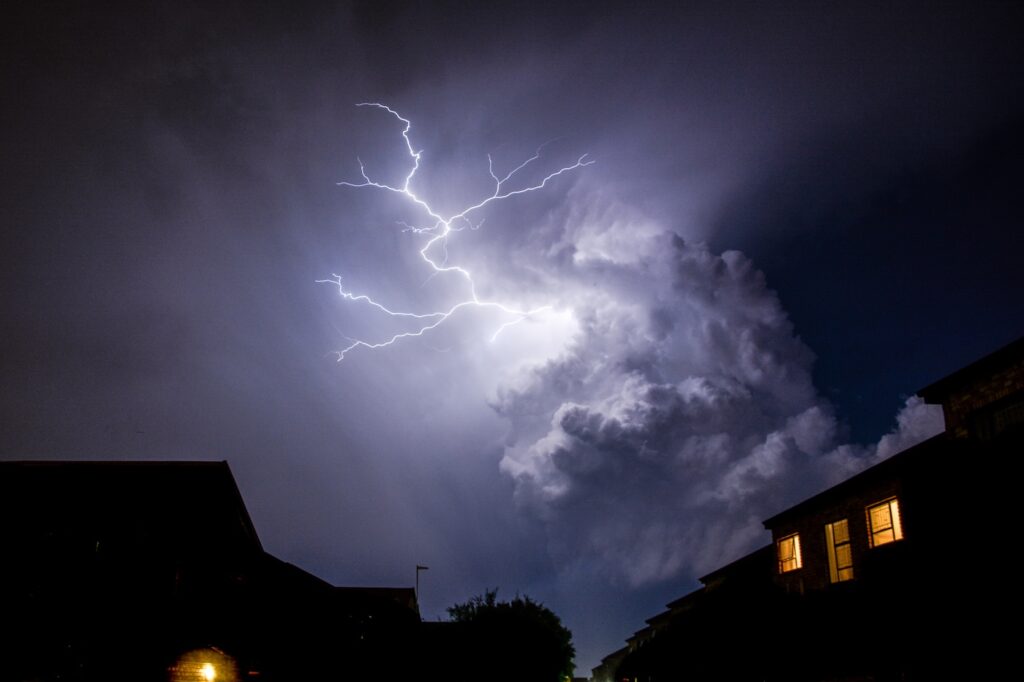 Lightning in dark sky above residential neighborhood at night