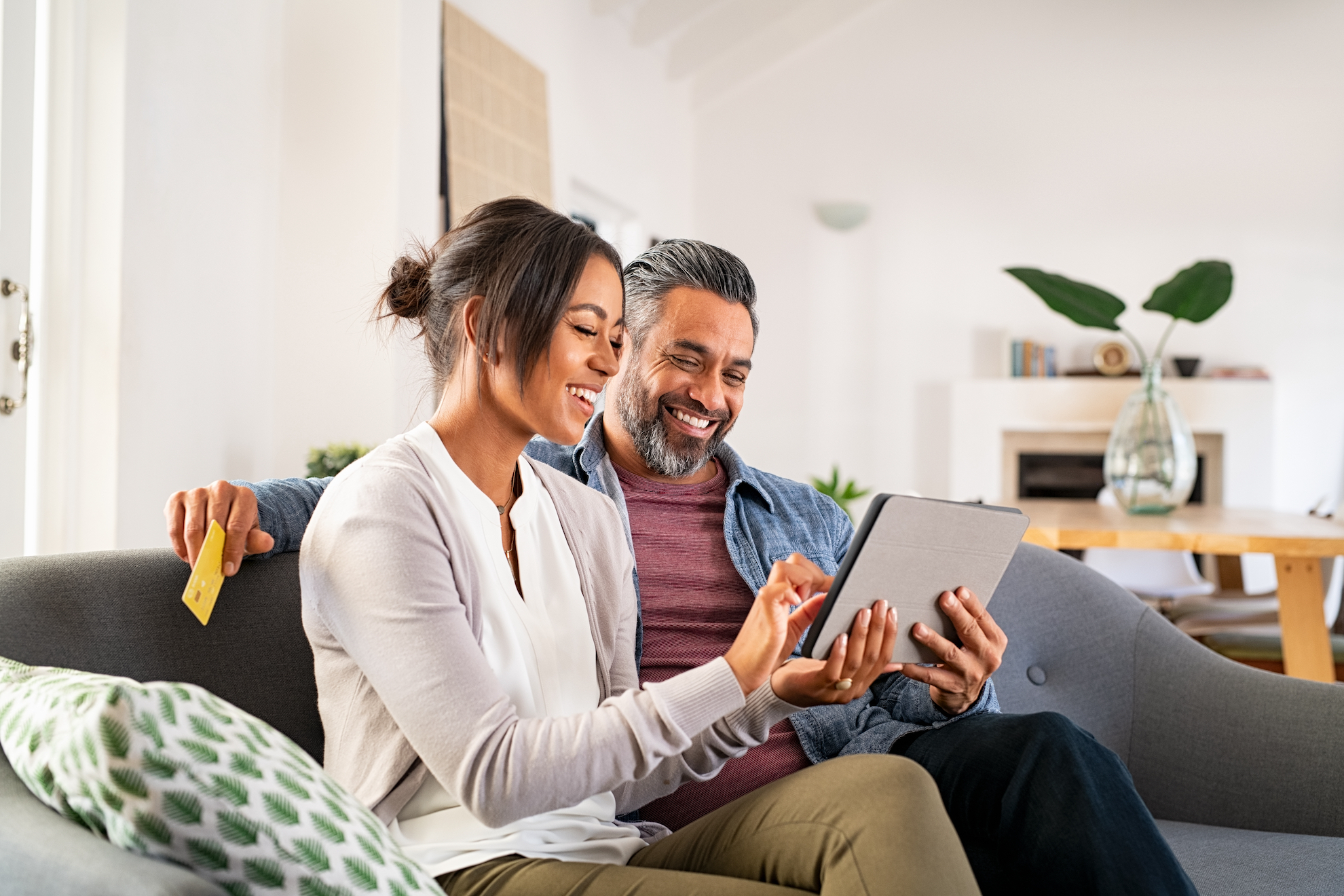 couple in their home on a couch looking at tablet