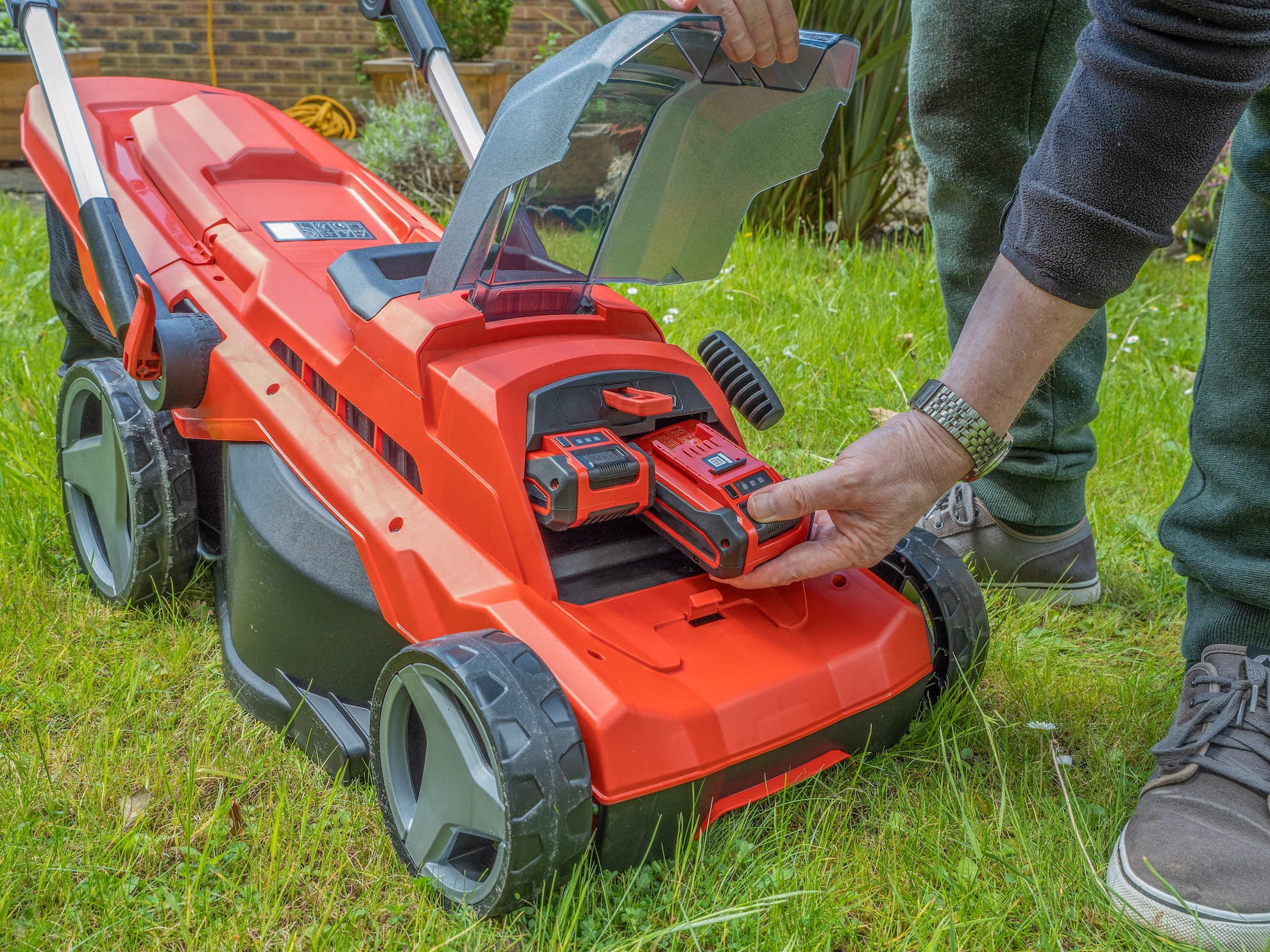 man putting new battery in his battery powered lawn mower