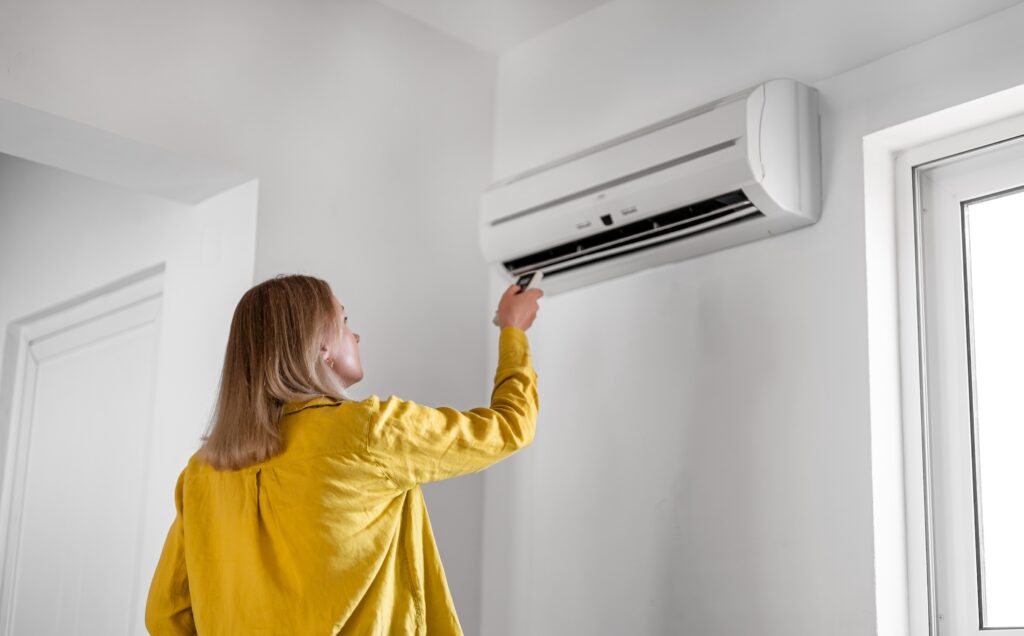 women in yellow shirt turning on heat pump air conditioner