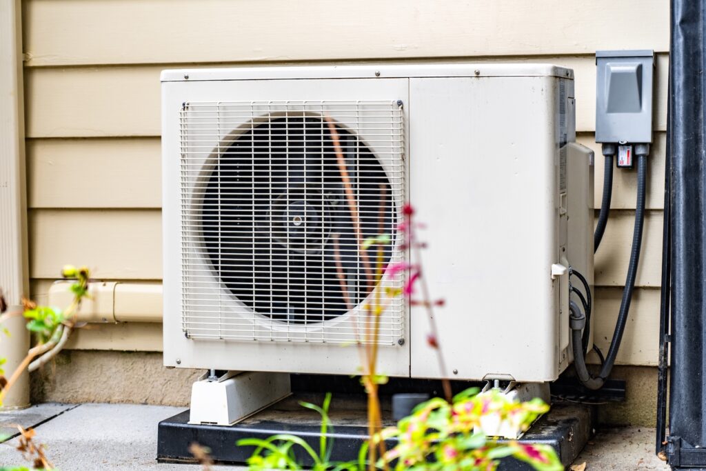 newly installed beige heat pump external unit on the side of a yellow-ecru home