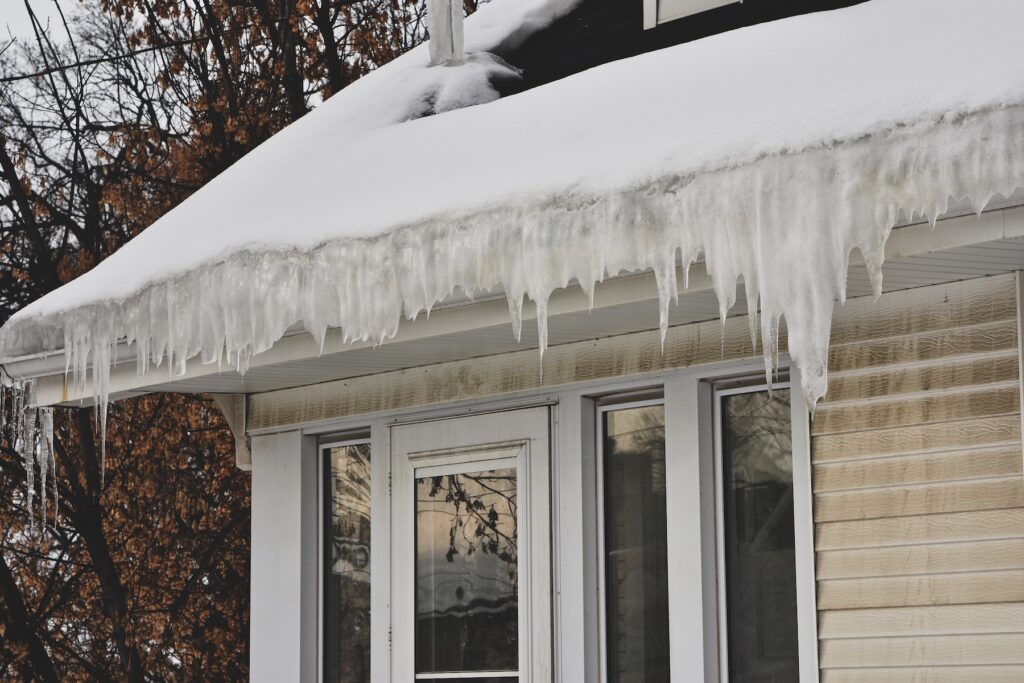 Melting snow on roof creating ice dam in gutter with possible water damage inside