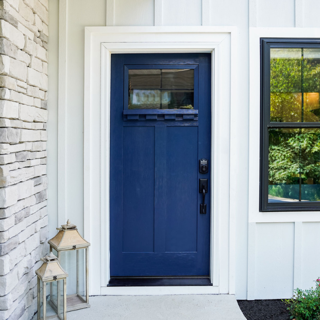Blue front door on home with white siding and light brick facade