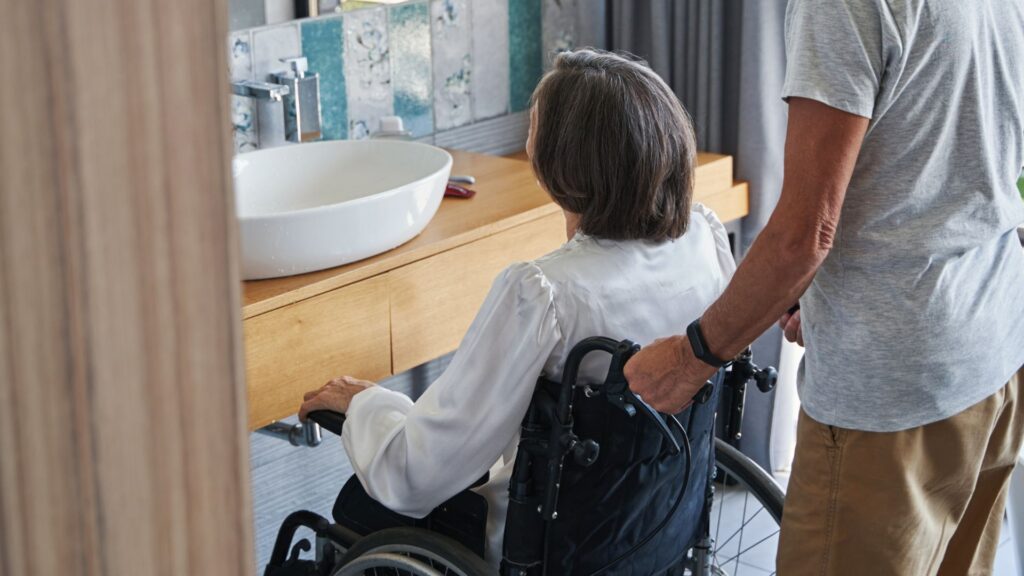 women in a wheelchair in her new bathroom that is wheelchair accessible