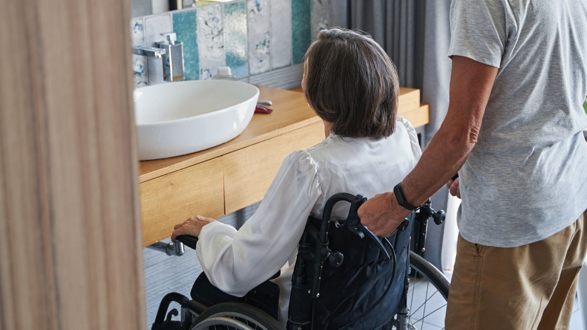 women in a wheelchair in her new bathroom that is wheelchair accessible